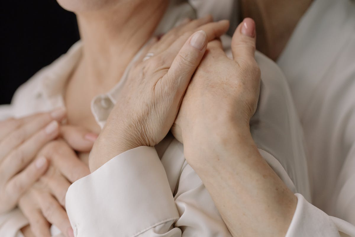 Two pairs of hands gently clasped together in comfort
