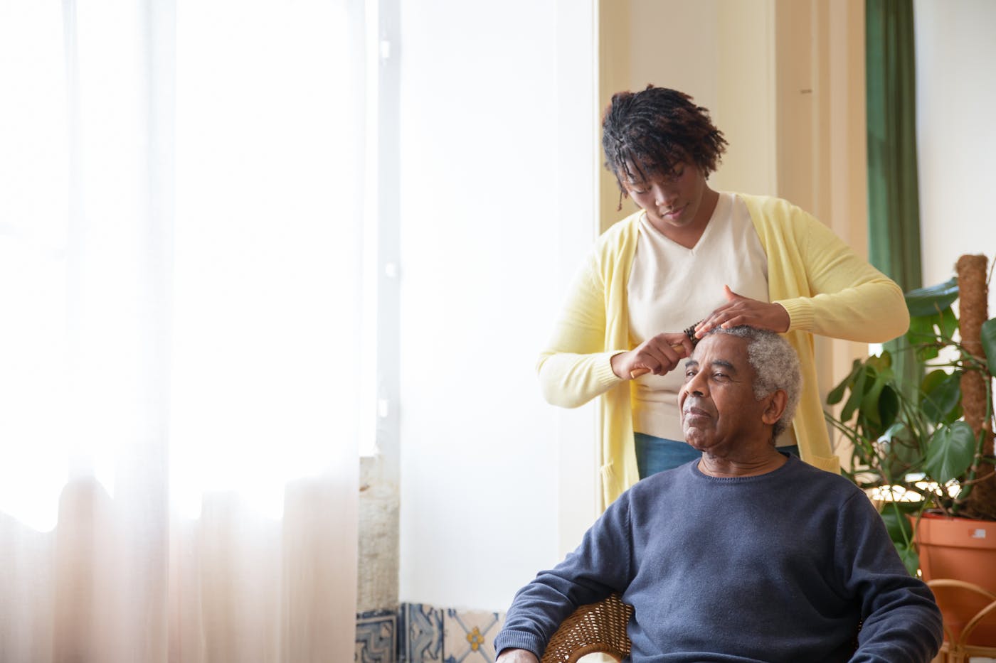 A daughter gently tends to her father's hair in soft morning light