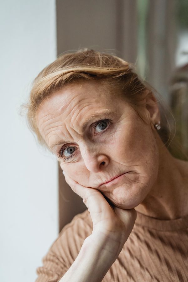 An older woman sits quietly with a worried expression